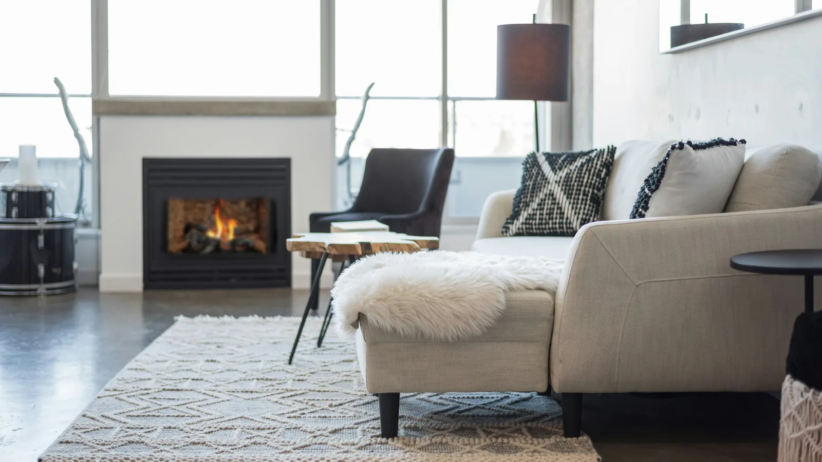 A living room with a stone fireplace, low sofas and a sheepskin throw