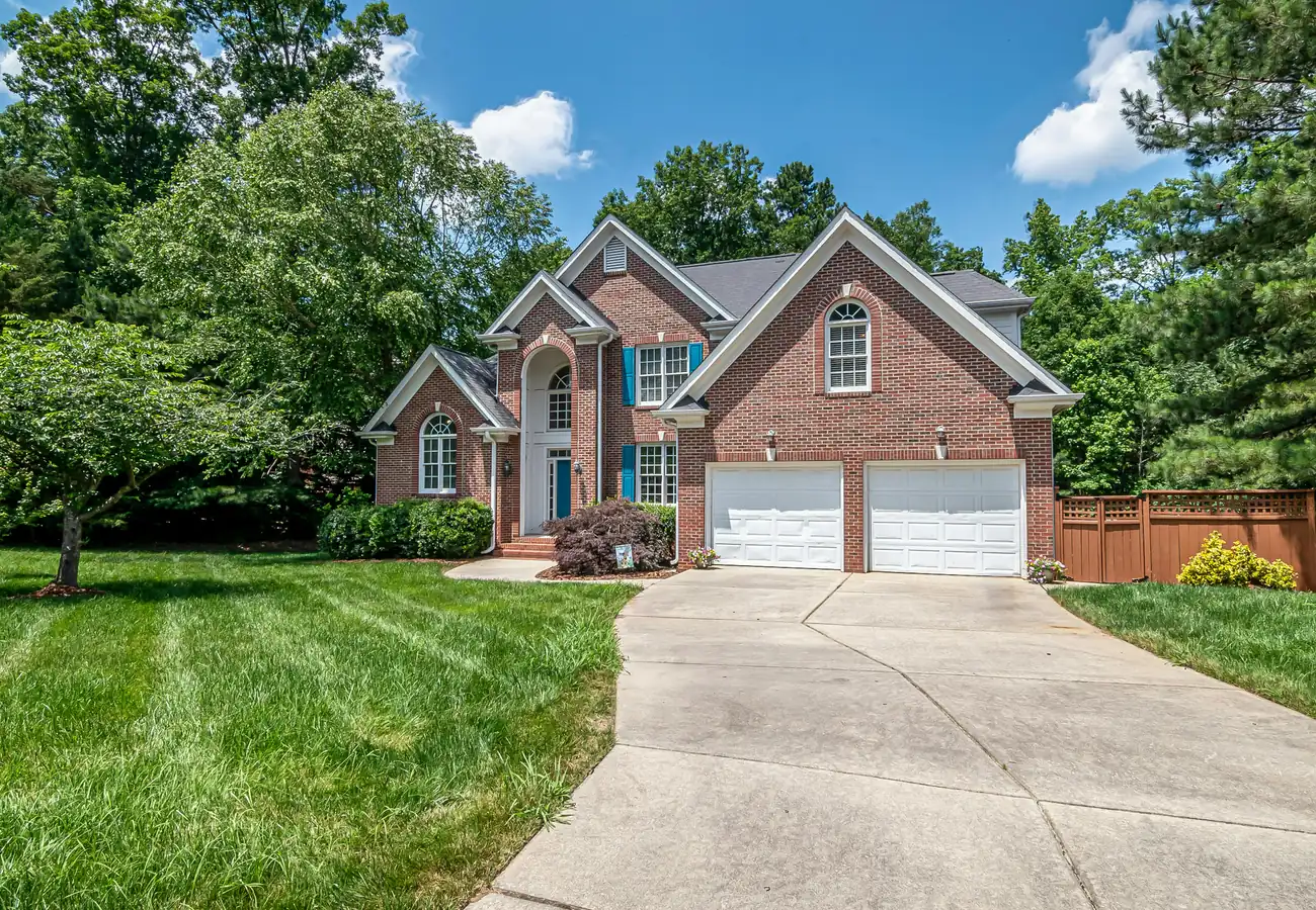 A two-story brick home with a double garage and a curved driveway