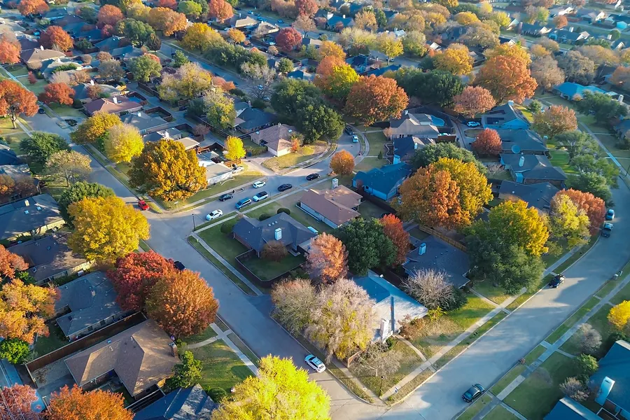 Aerial view of a tree-lined neighborhood with fall color and curving streets, representing buying a home in Whitney.