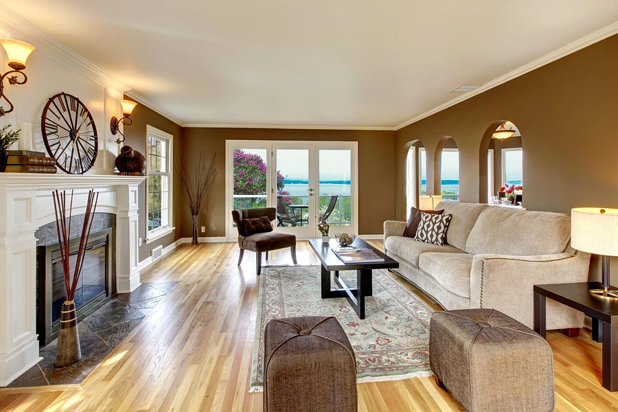 Living room with a white fireplace mantel, hardwood floors and French doors opening to a water view, representing buying a home in Whitney.