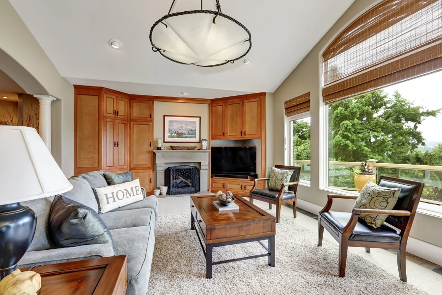 Living room with built-in wood cabinets, a fireplace and tall windows to the trees, representing preparing to list when selling a home in Whitney