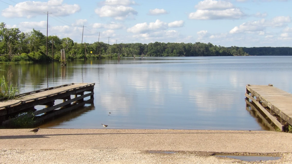Concrete boat ramp between two wooden docks on a calm lake, representing water access for White Bluff homes for sale
